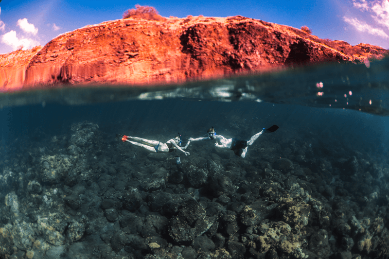 a couple of people snorkeling underwater at Molokini Crater