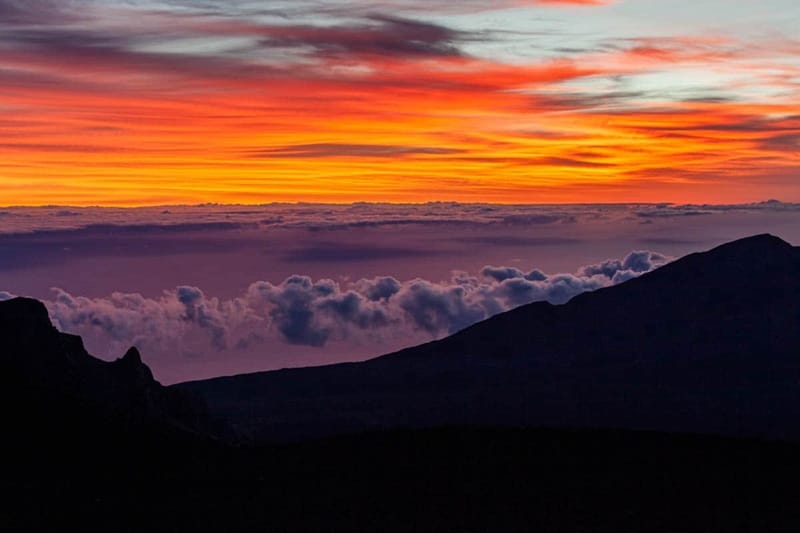 ハレアカラ山頂のプウ・ウラウラ(レッド・ヒル)から見た雲層の上からの日の出。. ハレアカラ山頂のプウ・ウラウラ(レッド・ヒル)から見た雲層の上からの日の出。.