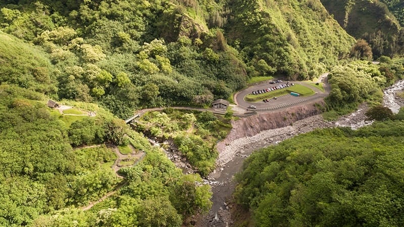 Vista aérea del Monumento Estatal del Valle de ʻĪao que muestra el área de estacionamiento, los senderos pavimentados y el arroyo ʻĪao en Wailuku, Maui.