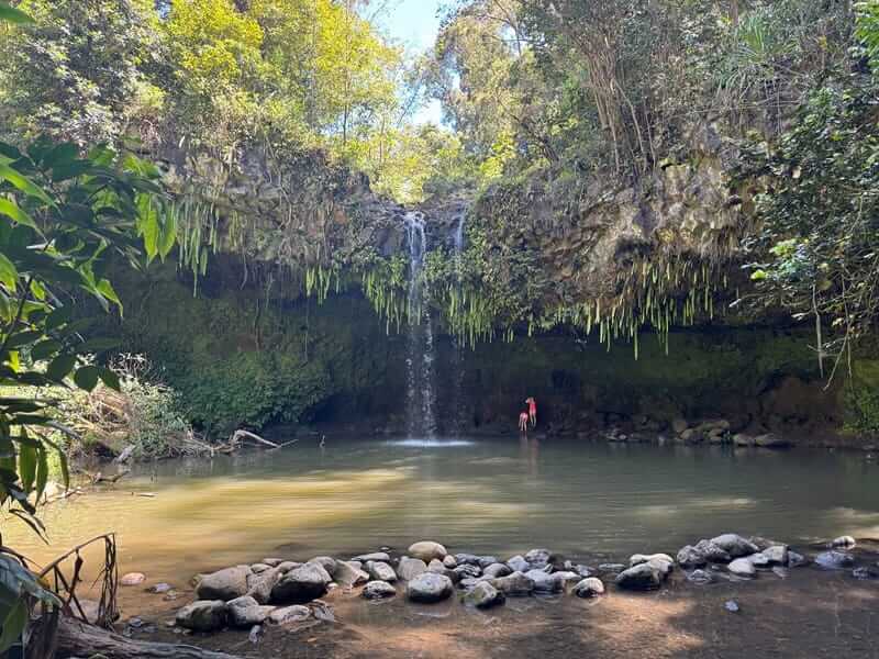 Waterfall and pool at Twin Falls Maui with person standing in the water