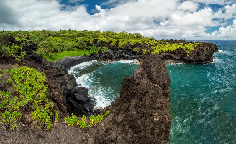 Rocky black lava coastline with turquoise water and small cove in Waianapanapa Maui