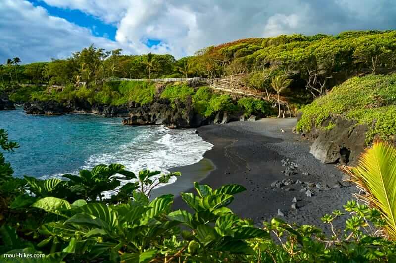 Black Sand Beach at Waianapanapa State Park, Maui, with ocean waves and lush coastal cliffs