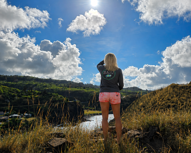 Person overlooking valley from West Maui Mountains with clouds and lush landscape