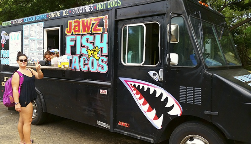 Black Jawz Fish Tacos food truck on Maui with colorful signage and a woman standing near the order window.