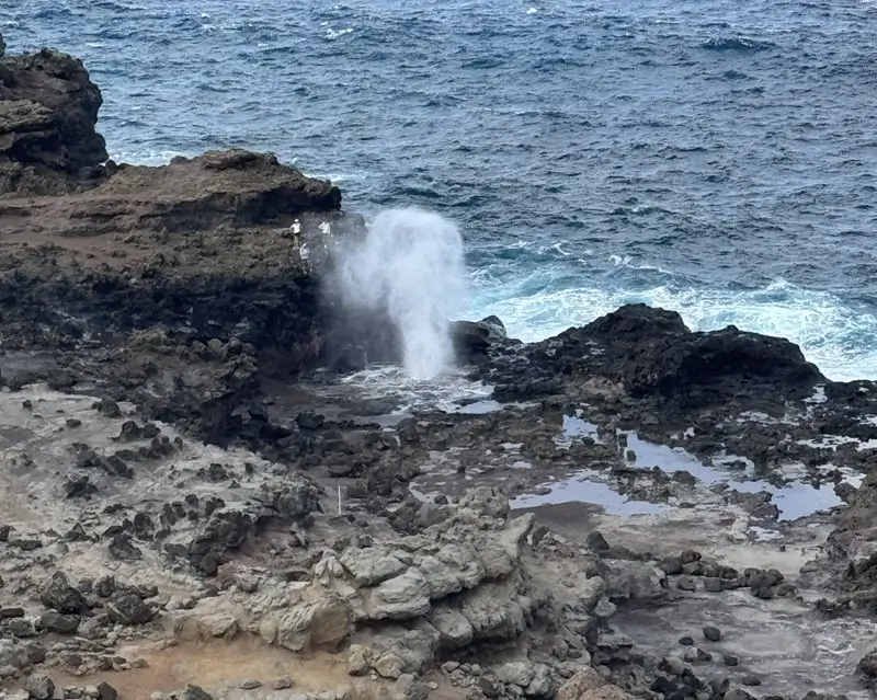 Nakalele Blowhole sprays from dark lava rock beside the ocean on Maui’s rugged northwest coast as waves break below