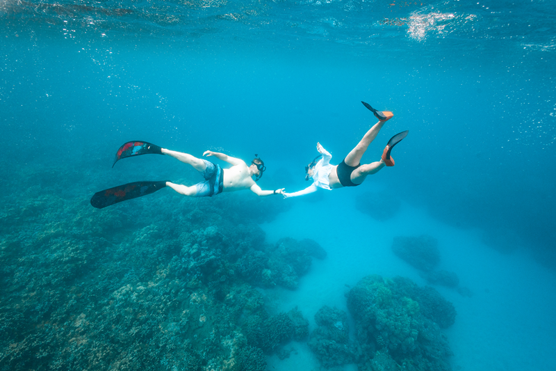 Two snorkelers exploring a coral reef while comparing Maui snorkeling destinations